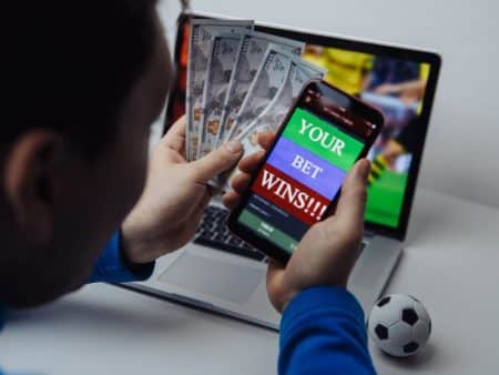 Man holding mobile phone and laptop on the background place a bet online