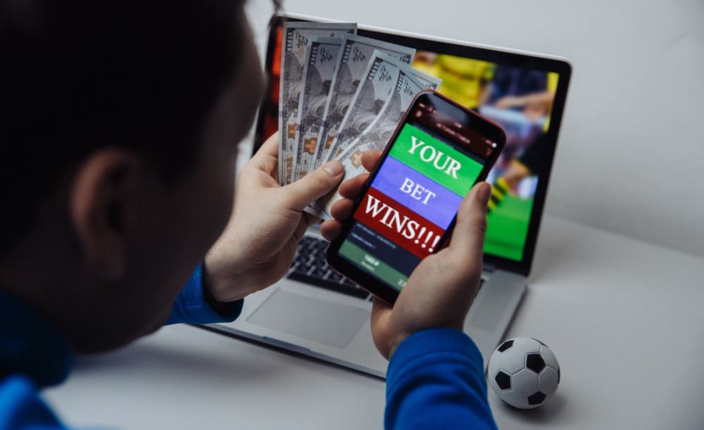 Man holding mobile phone and laptop on the background place a bet online
